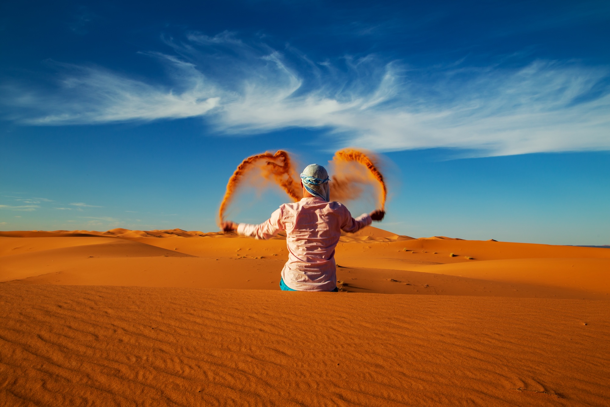 Single,Man,Throws,Sand,In,The,Sahara,Desert,At,Sunset.